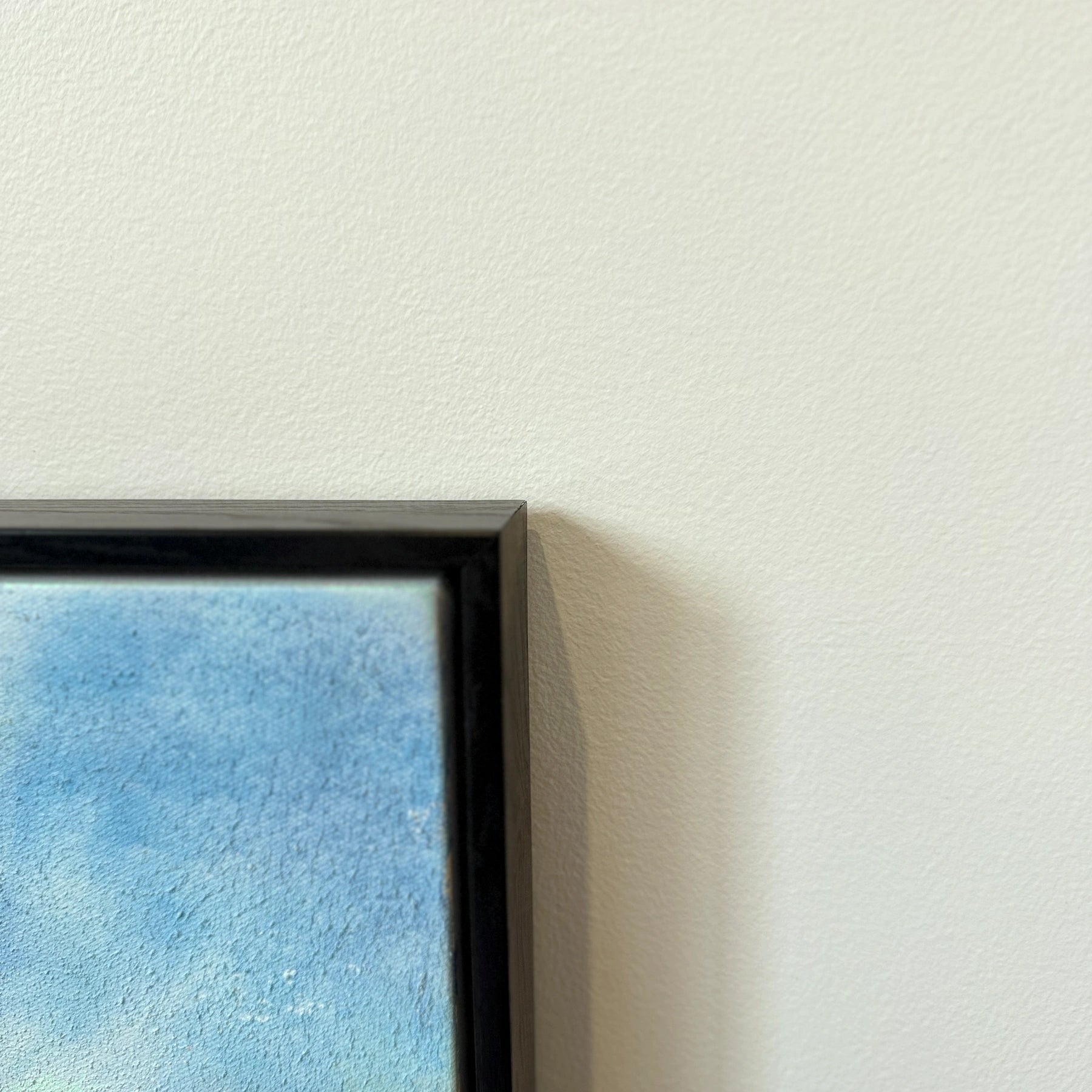 Corner detail of Misty Dawn textured seascape painting in a black wood finish frame